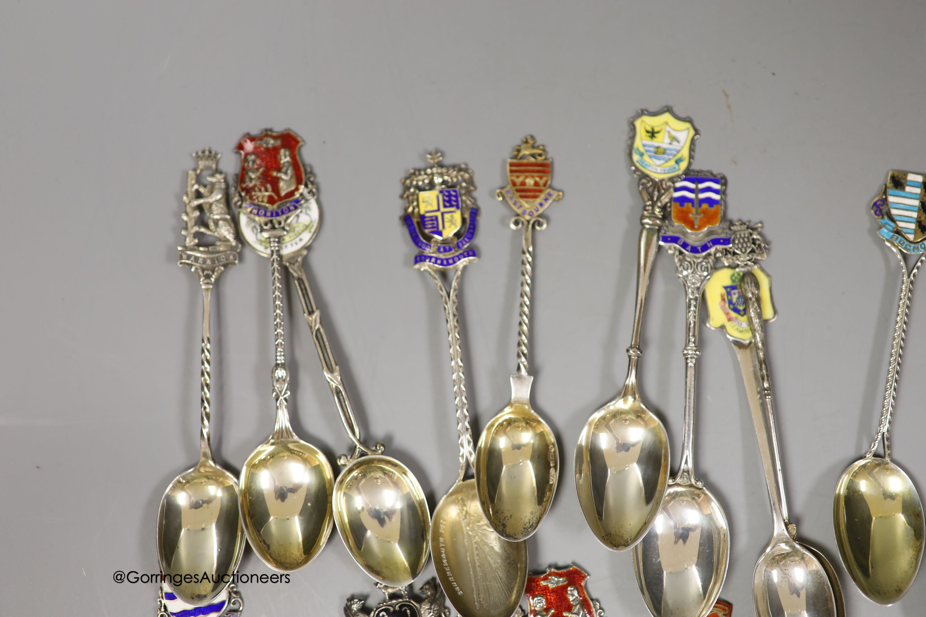 Twenty five assorted 20th century silver and enamel souvenir spoons, including Brighton, Bournemouth, Eastbourne, Chichester etc. and and Edward VII Coronation spoon, together with a similar white metal spoon, gross weig